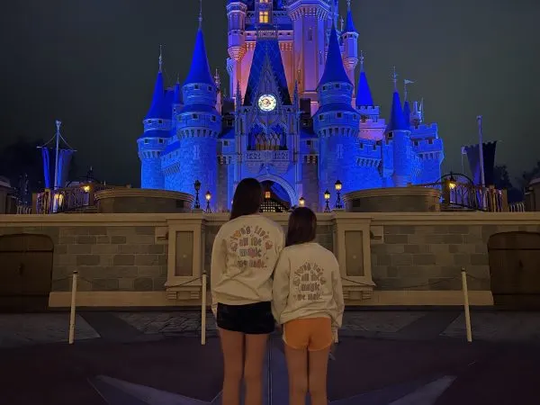 Annabel and her sister in front of the castle at night

