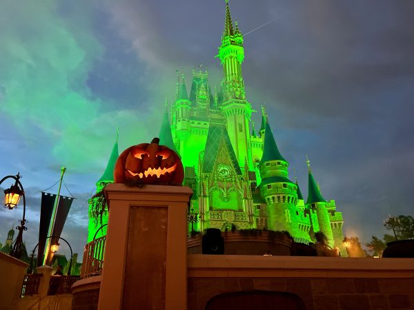 cinderella castle with green lights at mickey's not so scary halloween party