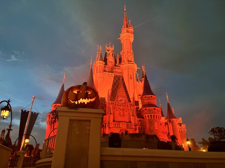 cinderella castle with orange lights at mickey's not so scary halloween party