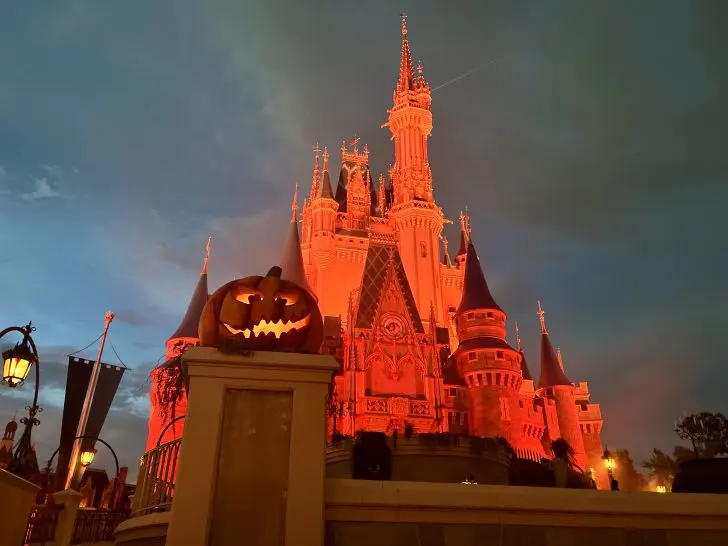cinderella castle with orange lights at mickey's not so scary halloween party